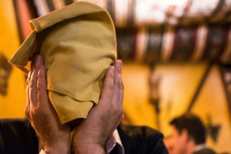 a person holding up a yellow mask that is covering his face