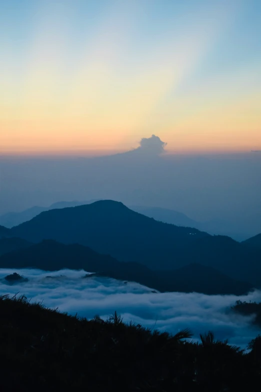 a mountain peak has fog coming out from below