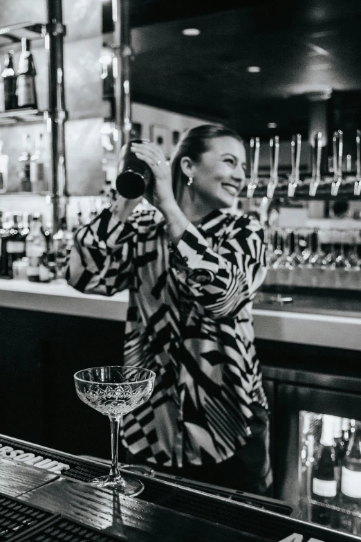 black and white pograph of woman at bar holding glass with wine