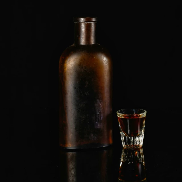 a glass and bottle on a dark surface