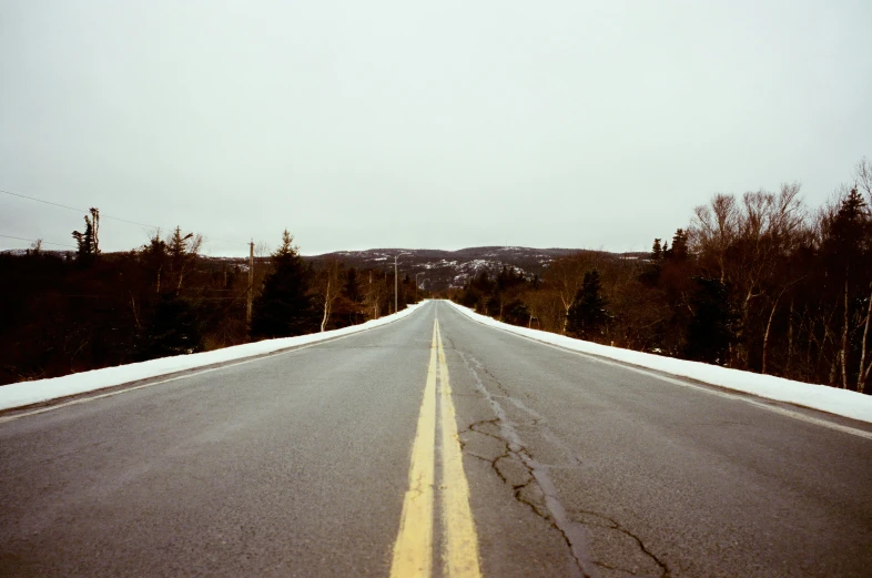 a snowy road with a road sign on the side