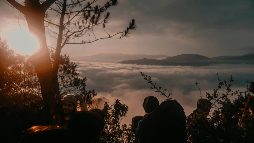 two people stand on the edge of a mountain with the clouds