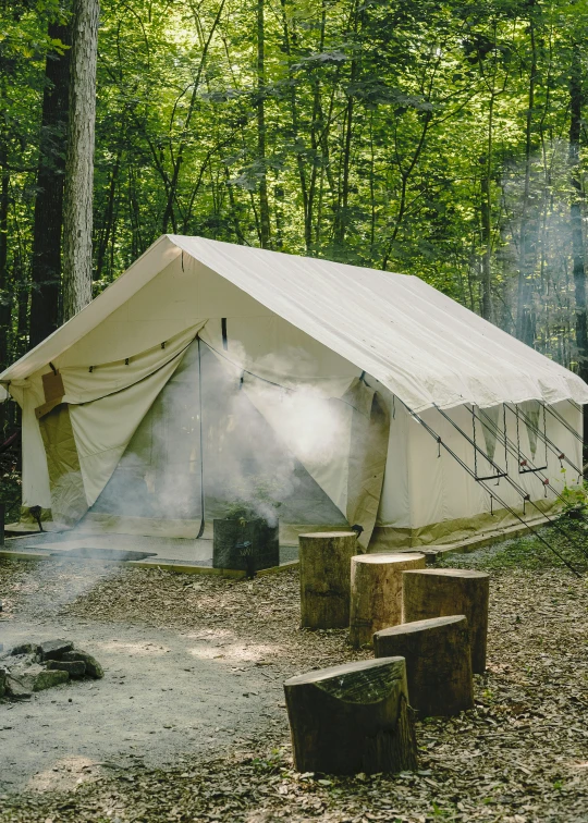 a large tent with smoke coming out of it in the middle of a forest