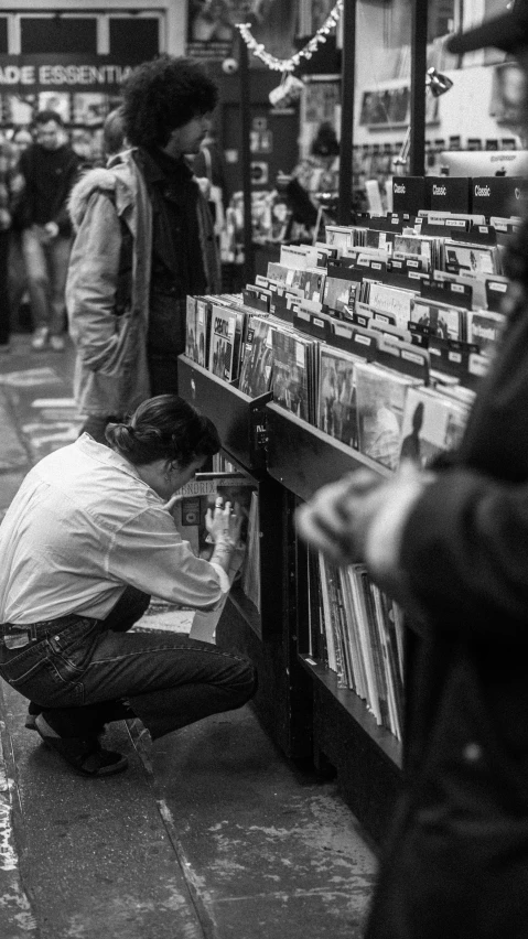 a person kneeling on the ground working on the cd rack