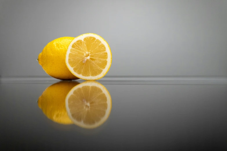 two whole oranges sitting on a reflective surface