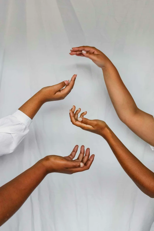 four hands reaching out into a ball