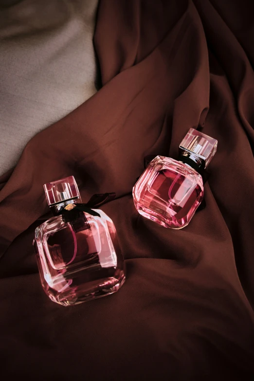 two different perfume bottles are on a blanket