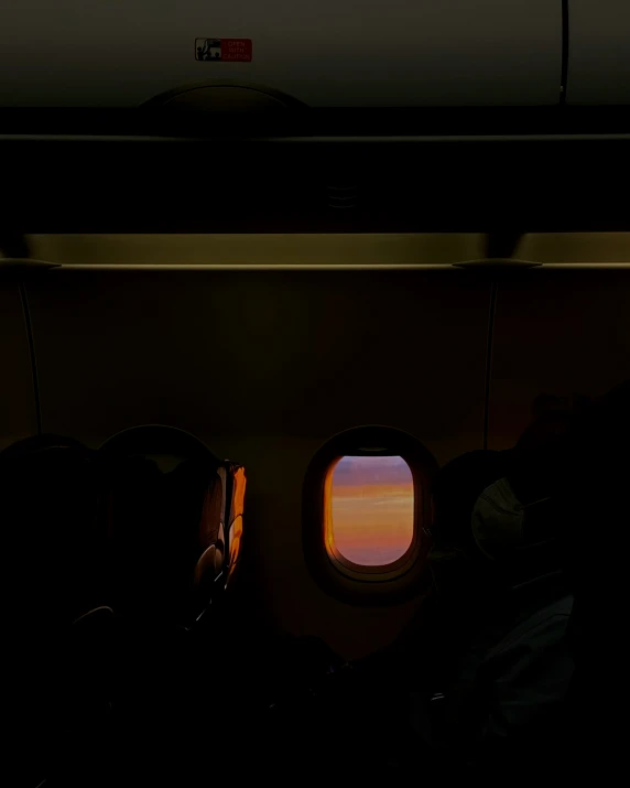 the silhouettes of two people in seats are shown through an airplane window