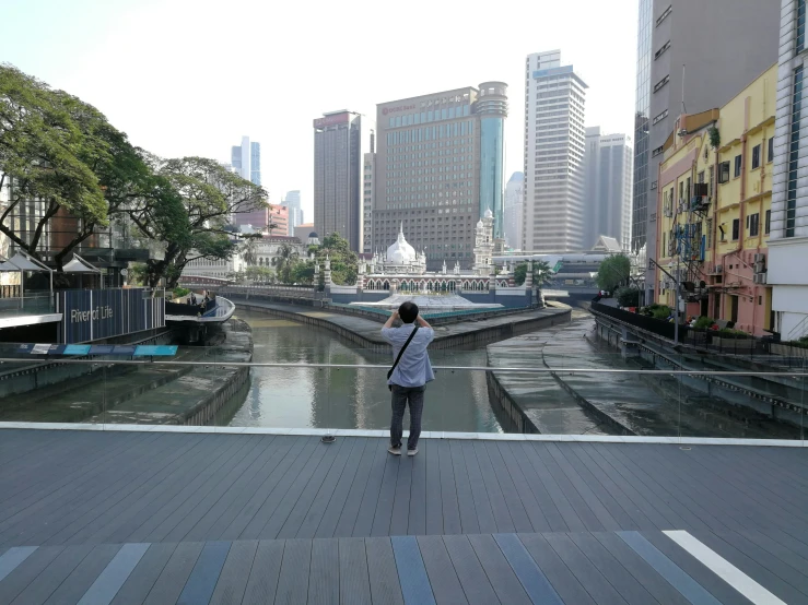 man standing on bridge with city in background