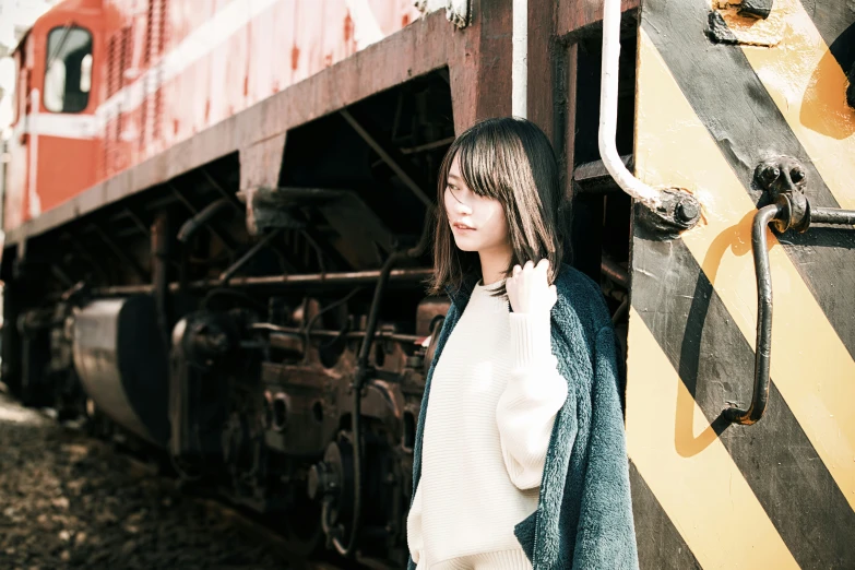 a woman is standing next to the rails of a train