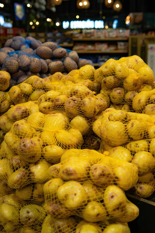 yellow potatoes sit on a table and are in mesh bags