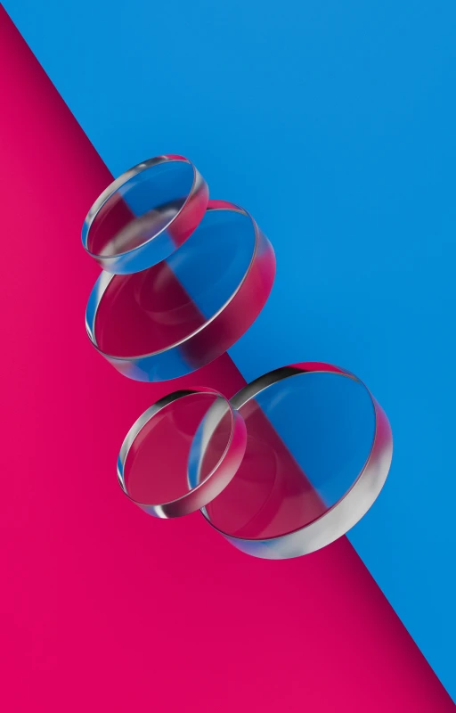 a pair of glasses lying on top of a bright pink and blue surface