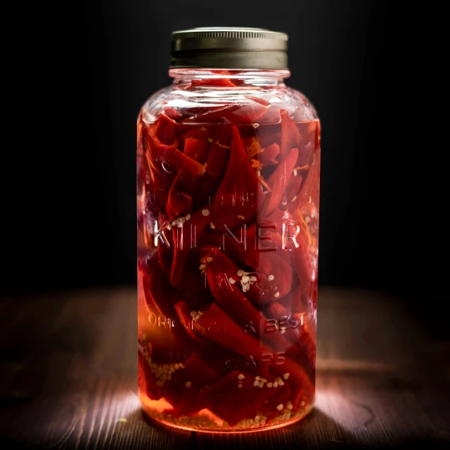 a jar with lots of red  peppers inside of it