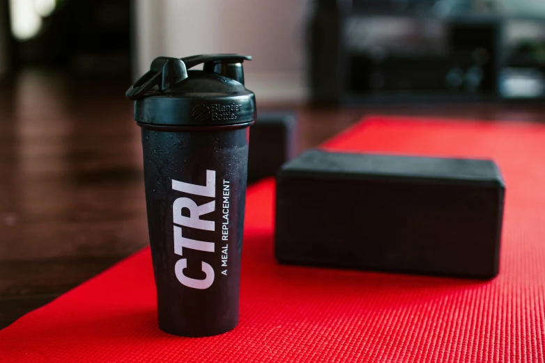 a black shaker bottle on top of a red mat