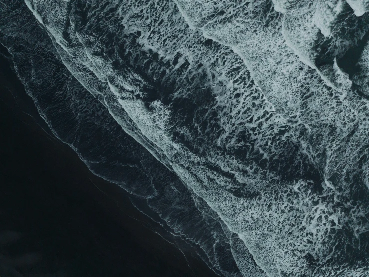 aerial view of the ocean waves crashing onto the rocks