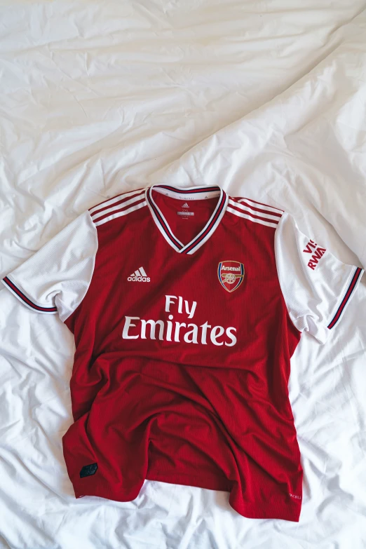 the red and white soccer jersey is lying on the bed