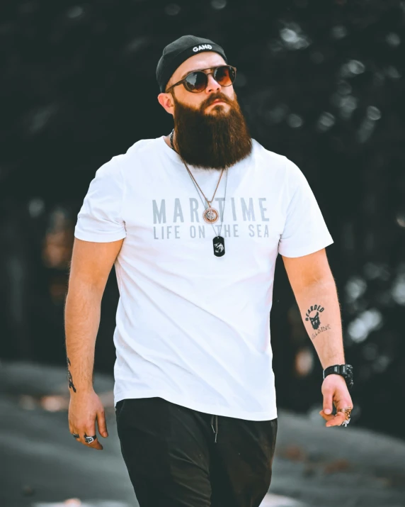 the bearded man in the t - shirt is walking down the street