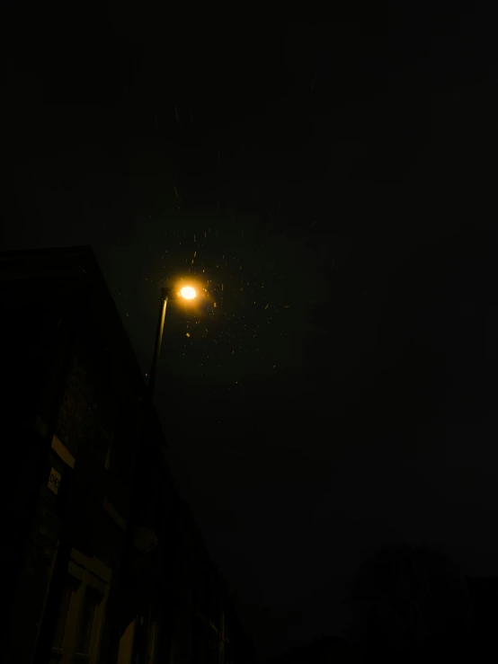 a night view of a street light with stars in the sky
