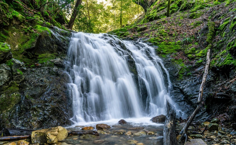 the water fall is flowing from the rock wall