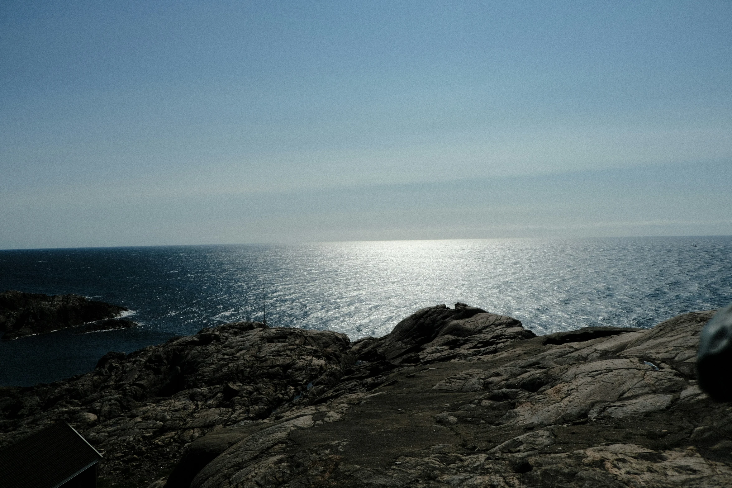 a rock is in front of the ocean with clear sky