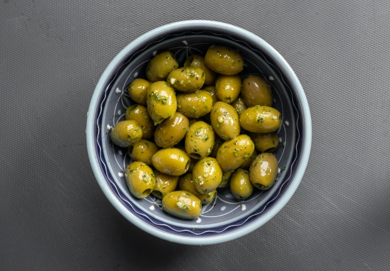 an overhead view of a blue and white bowl with olives in it