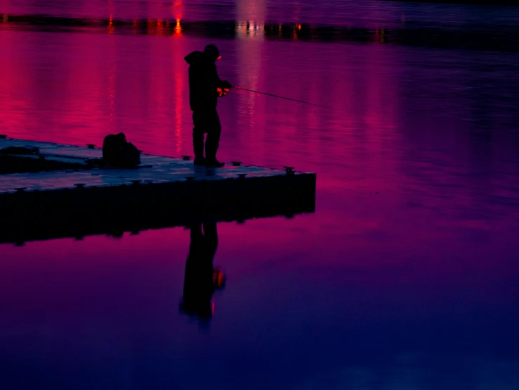 the man is standing on the dock fishing