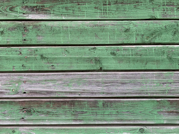 a green wood plank wall with a textured peeling paint peeling paint on it