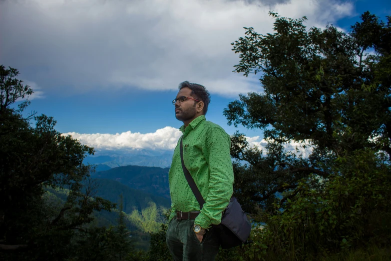 a man standing by some trees and clouds