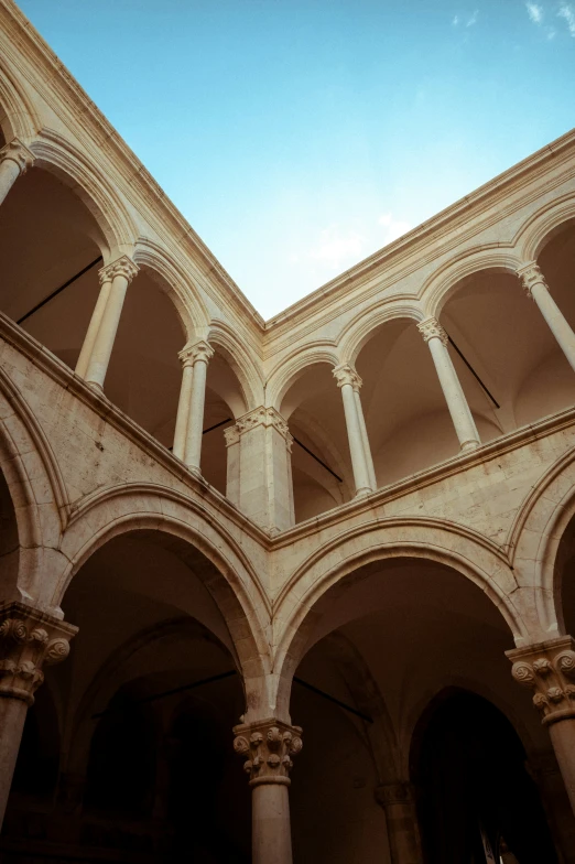 a room with many arches and pillars, and a bright blue sky