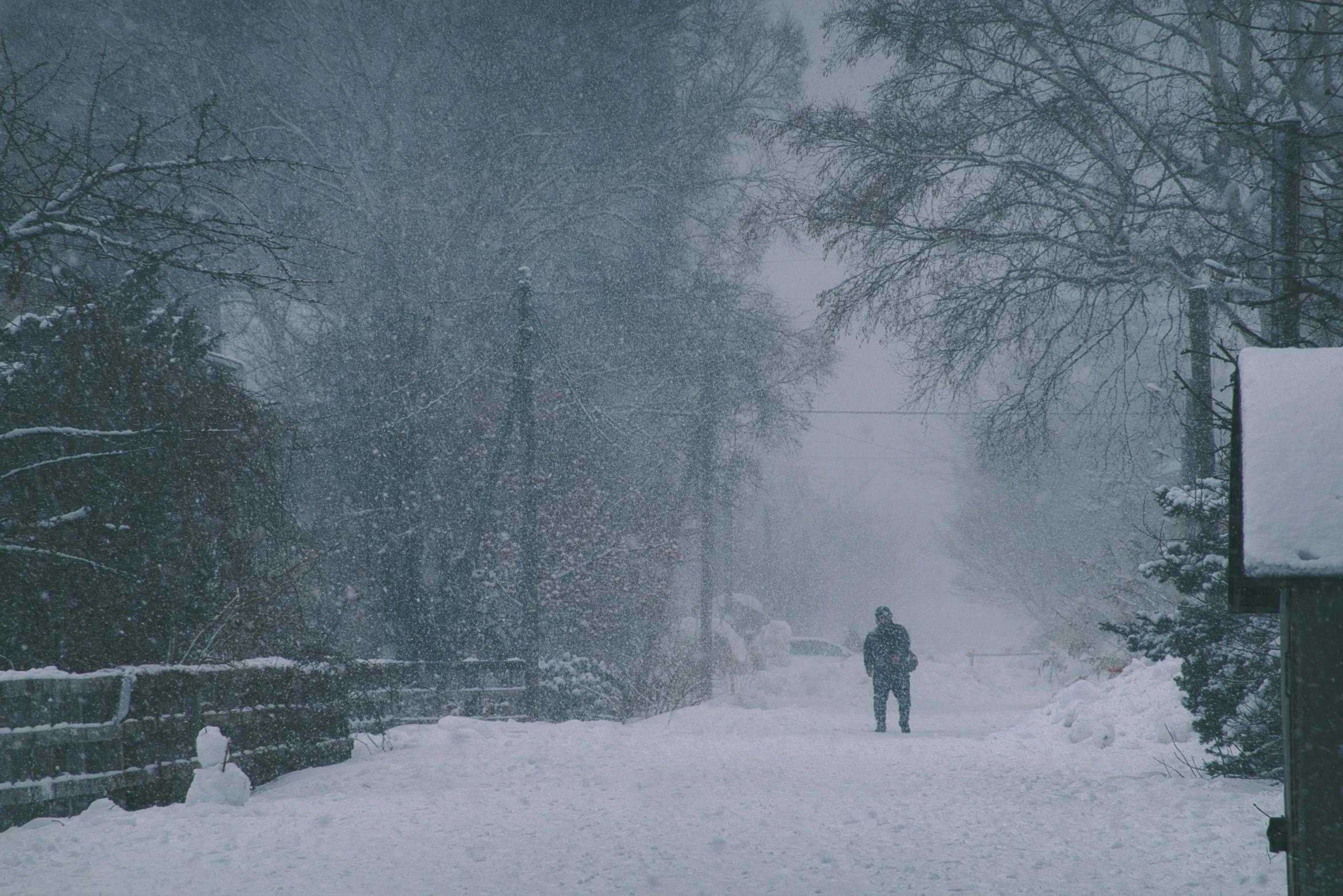 the lone man walks up the snow covered road