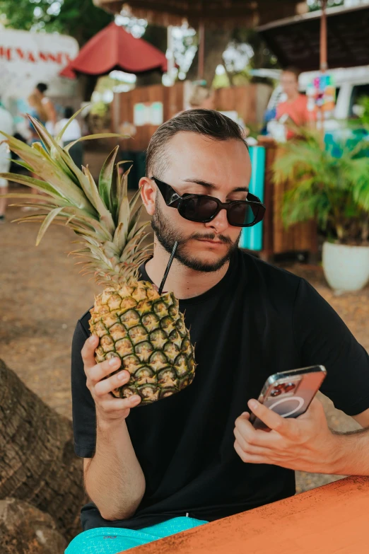 a man sitting at a table while holding a pineapple