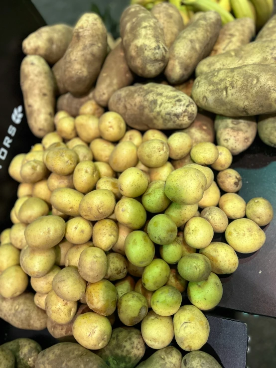 a pile of potatoes and green bananas are sitting on a table