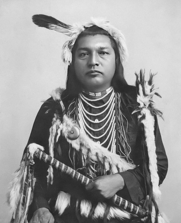 native american chief posing for a portrait wearing an elaborate headdress