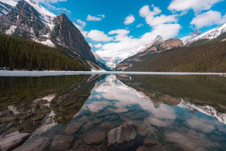 the mountains are snow covered and reflecting in a lake