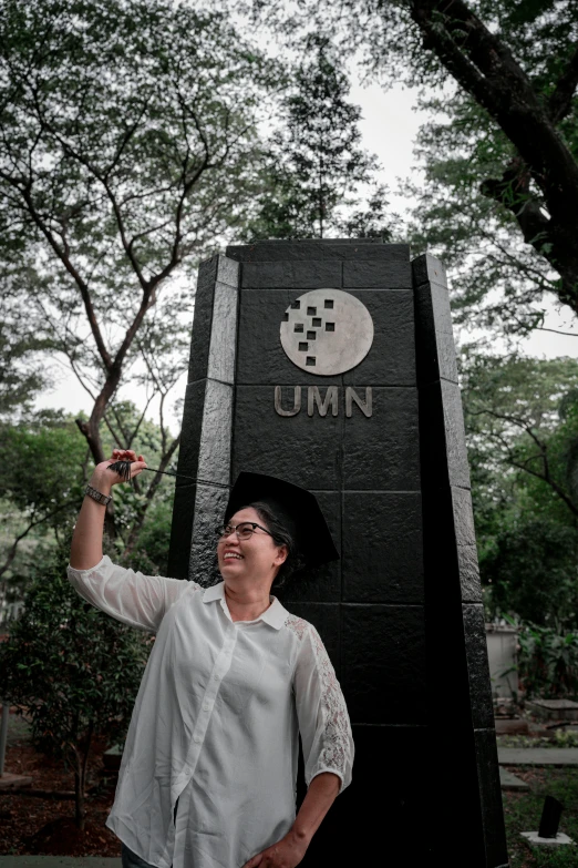 a woman wearing glasses is standing next to the umn sign