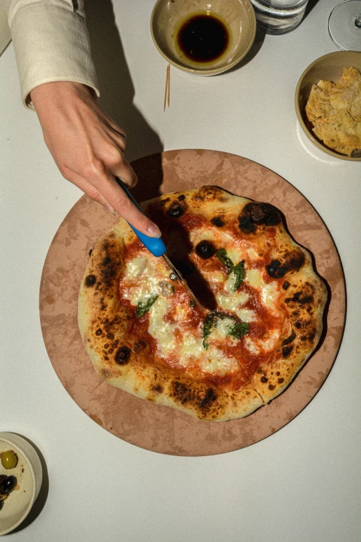 someone  a pizza on a plate with their knife