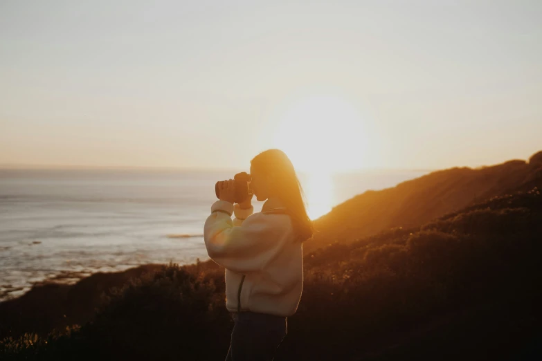 a woman taking a po of the sunset