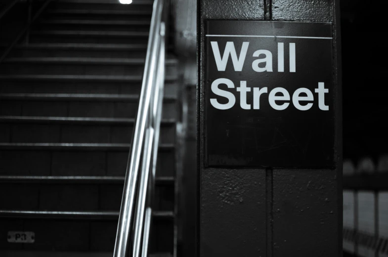 a sign that says wall street below a staircase