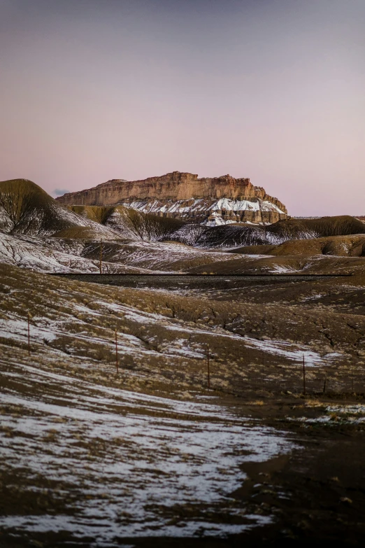 a landscape of snow capped hills with dirt and fence