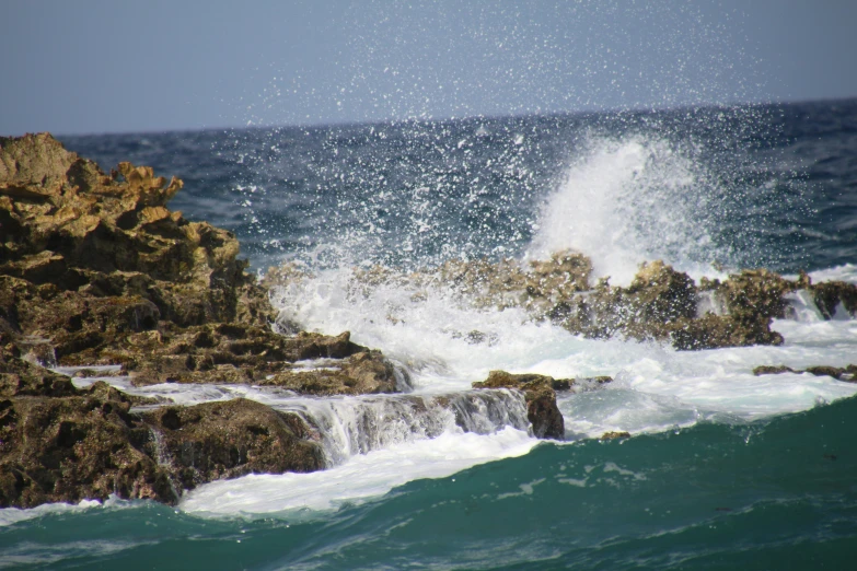 a large wave crashing on rocks at the ocean