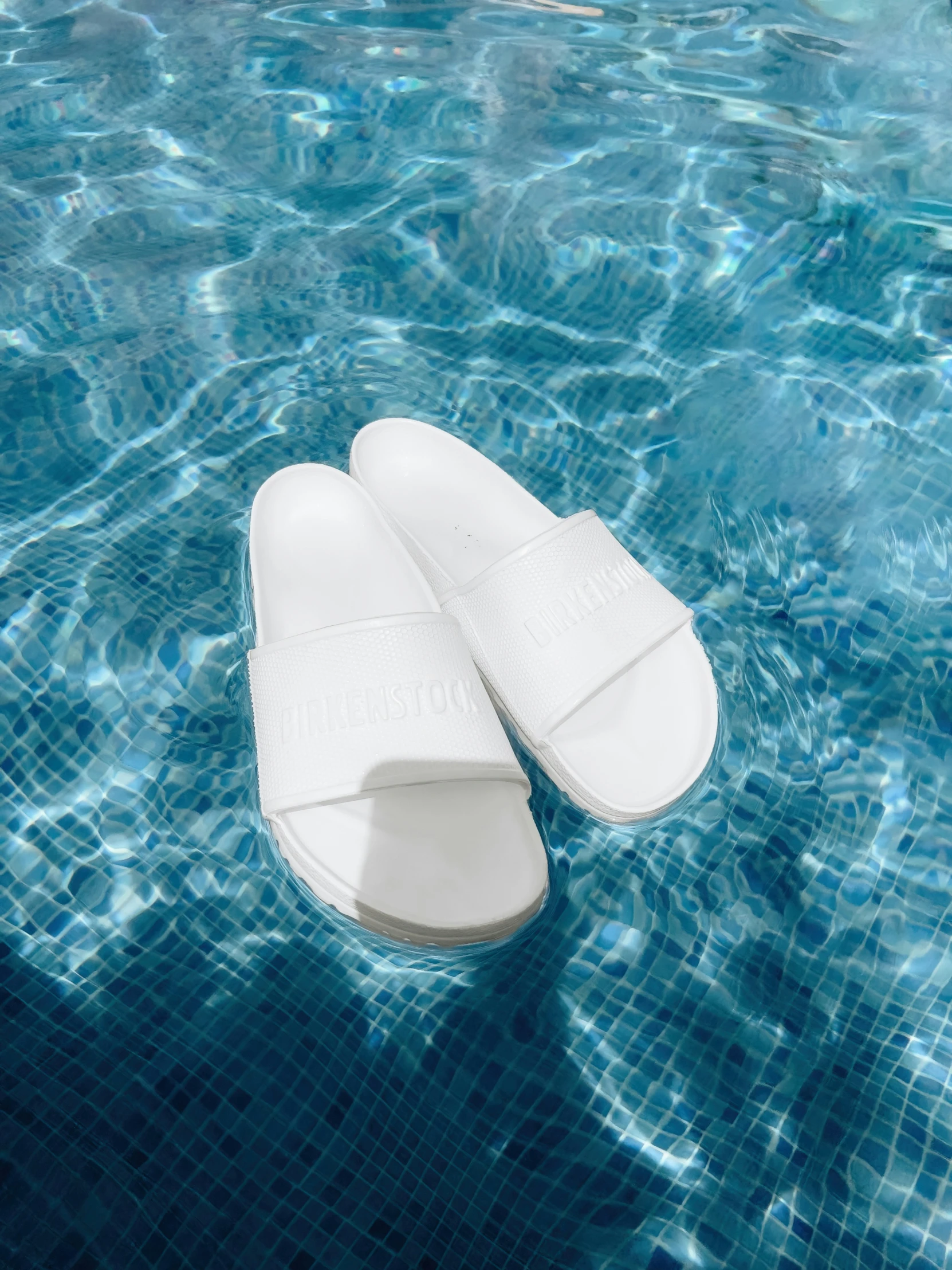 a pair of white shoes are lying on the side of a pool