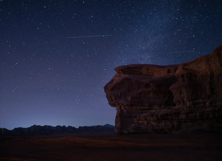 the sky and stars over some rocks in the desert