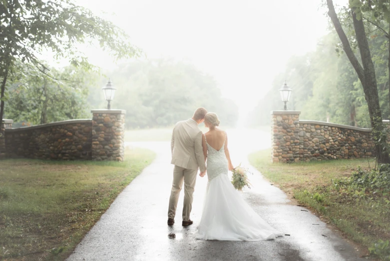 the bride and groom are standing together in the rain