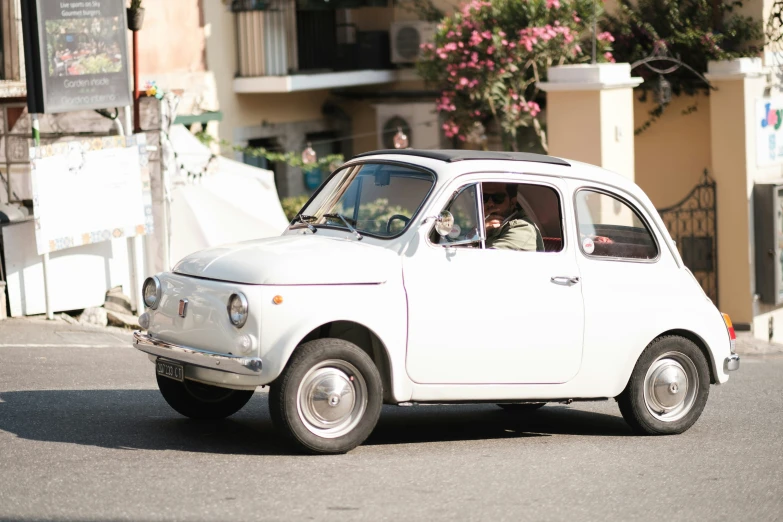 an old white car is driving down the street