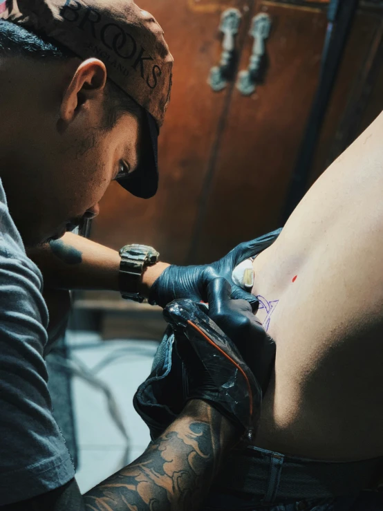 a man in cap doing tattoo on chest