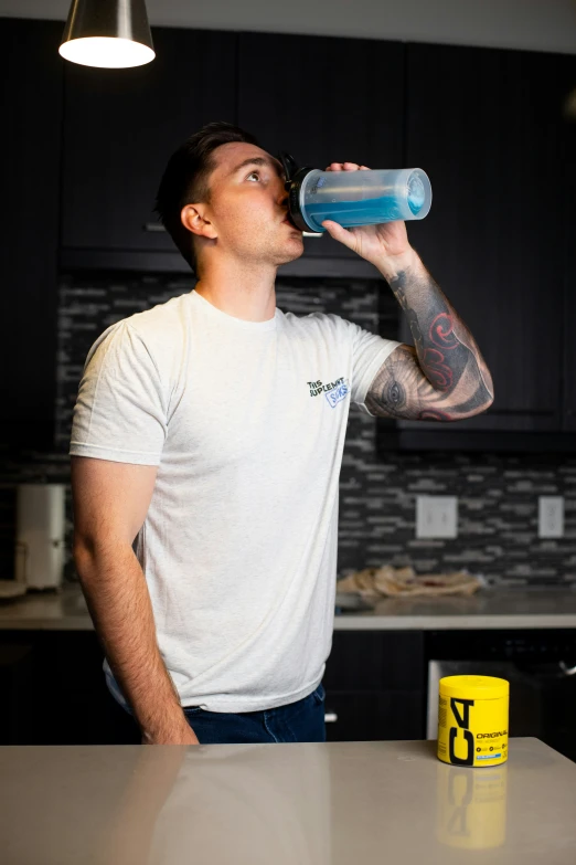 a man in a white shirt drinking water out of a bottle