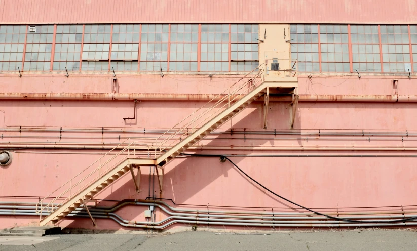 a fire escape next to a tall pink building
