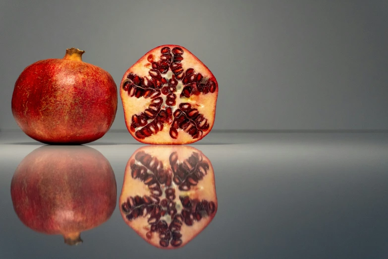 a red pomegranate on top of a shiny surface