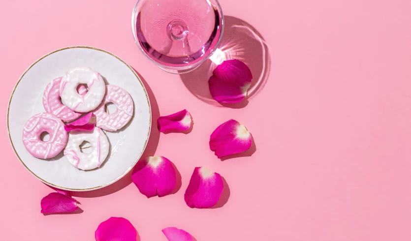 two donuts with icing on a plate next to petals