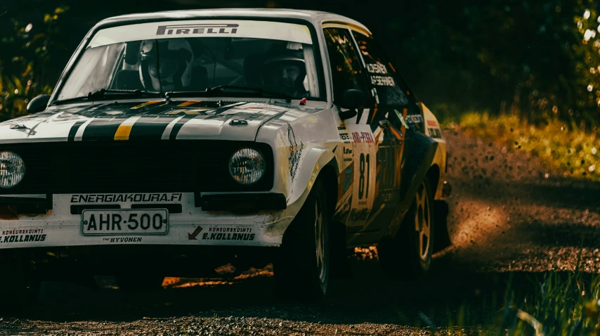 a white car with black stripes driving on dirt road